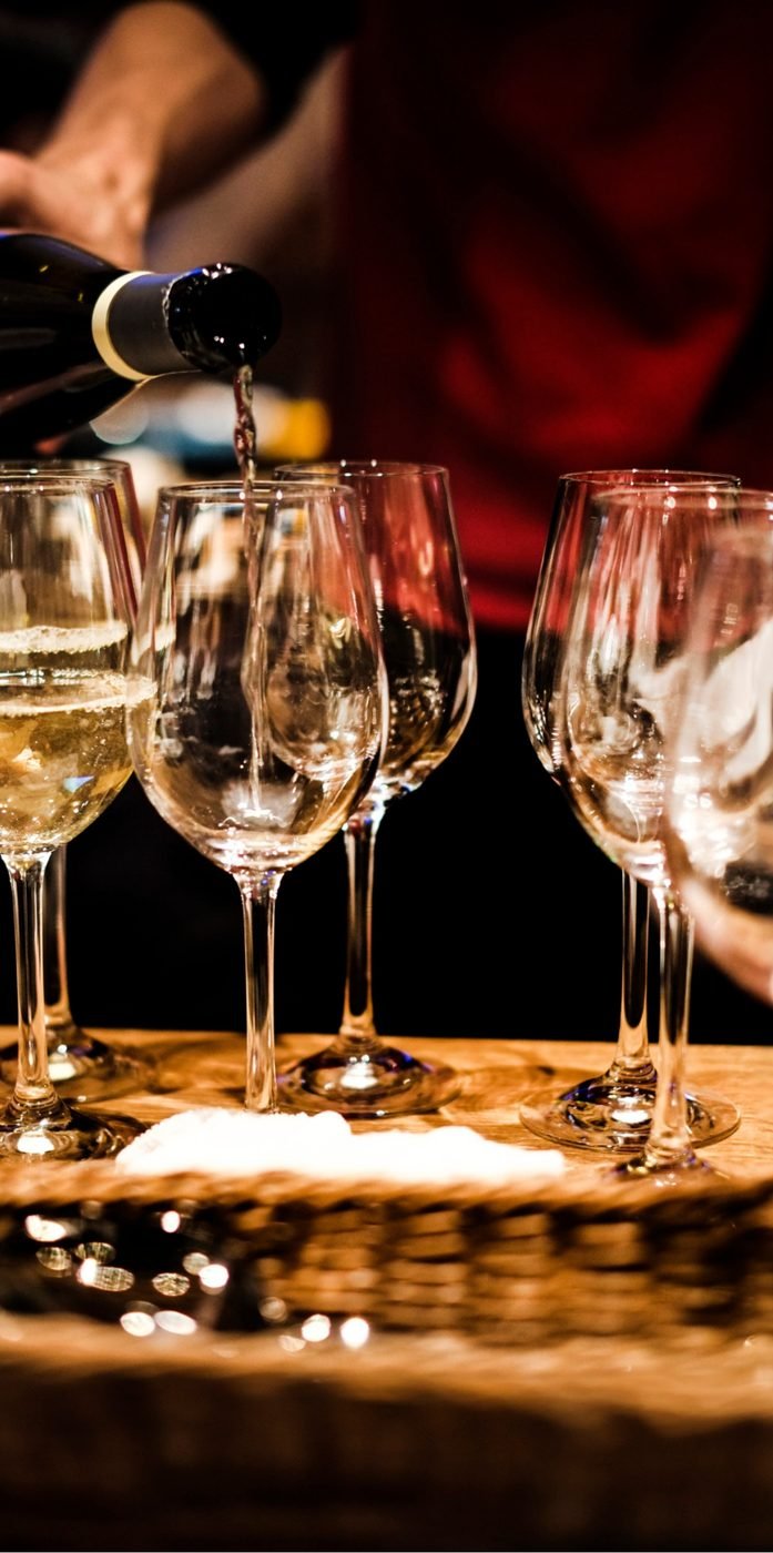 Wine being poured into a row of glasses